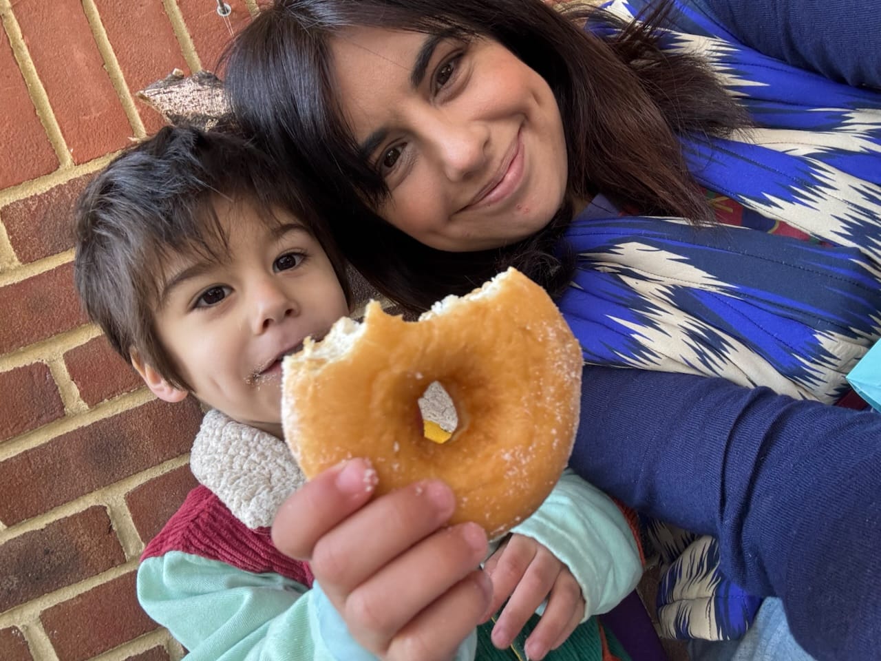 Anna and her son share a celebratory doughnut outside the nursery.