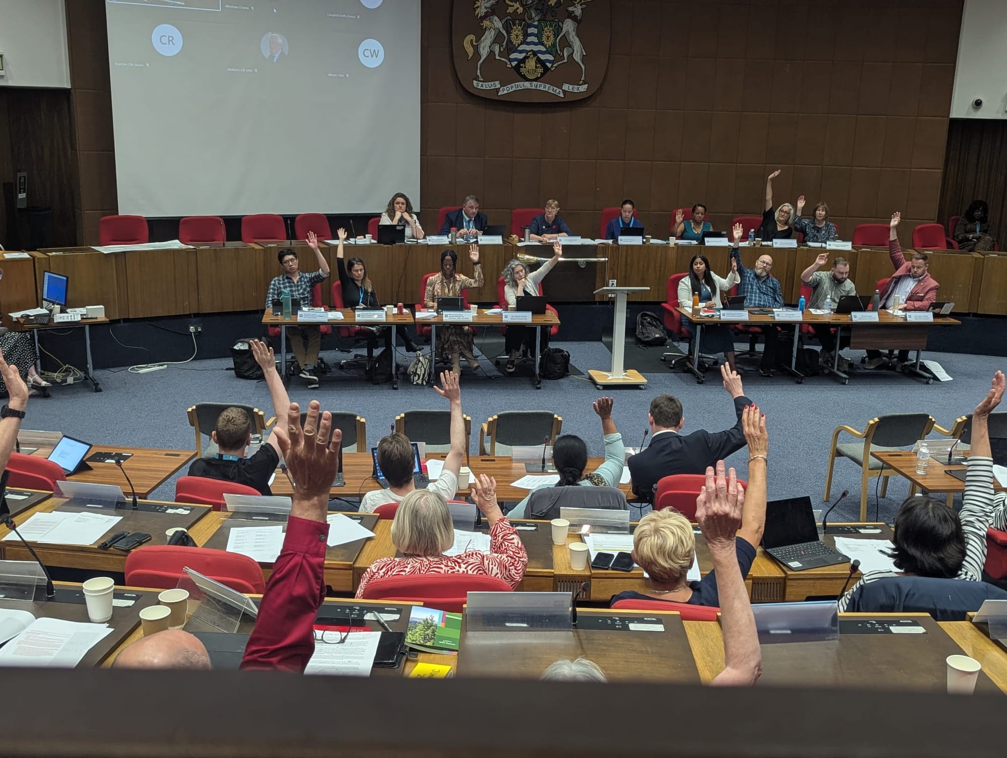 Councillors with raised hands at the meeting