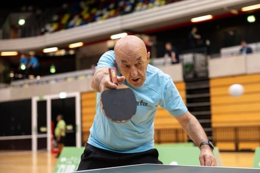 Older person playing table tennis.