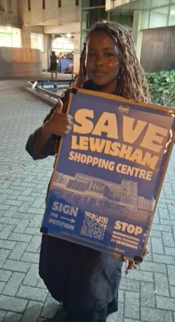 Young campaigner holding sign "Save Lewisham Shopping Centre" outside the meeting