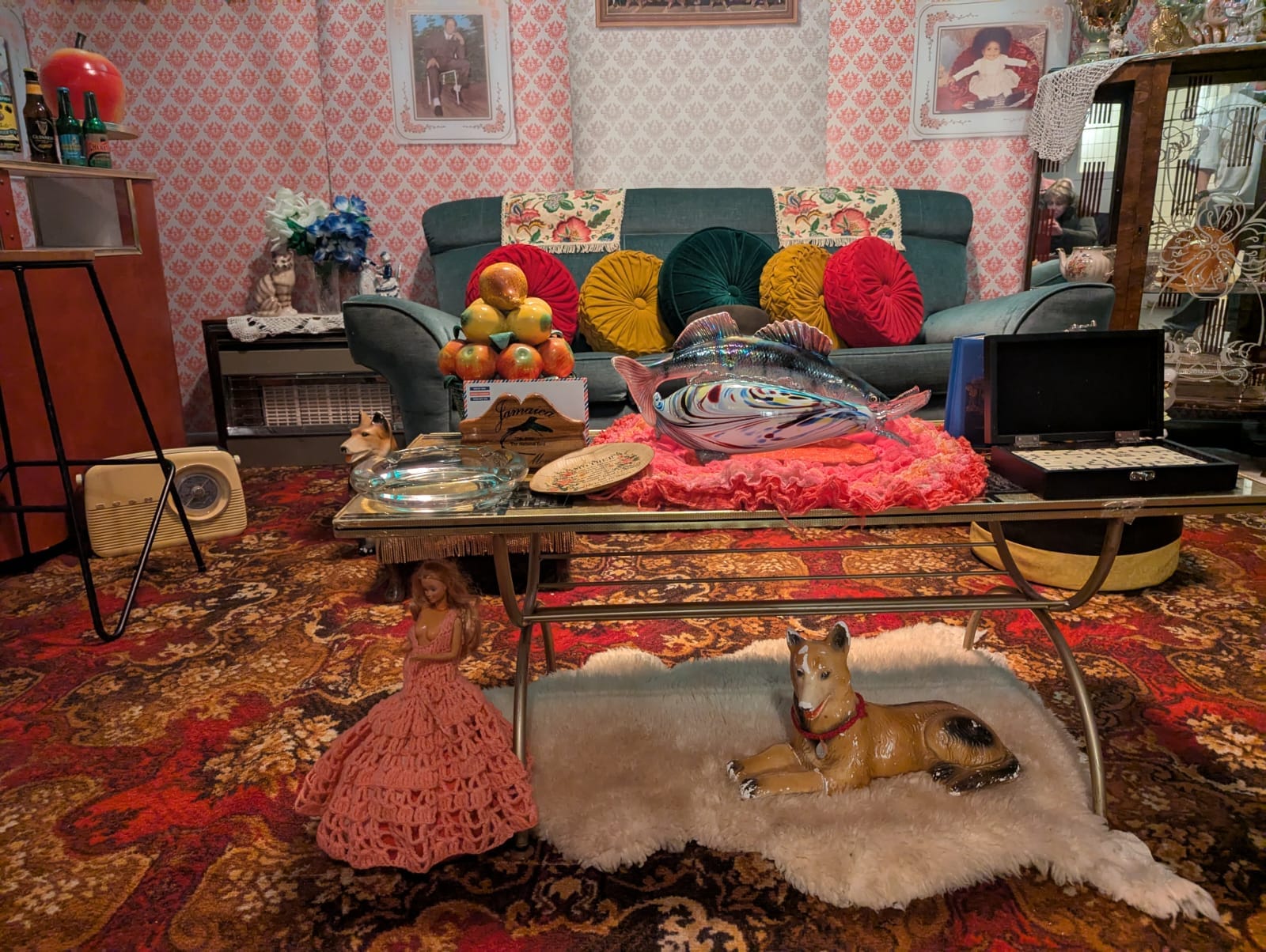 Glass coffee table crowded with ornaments, china dog on fur rug on floor and doll in crochet dress