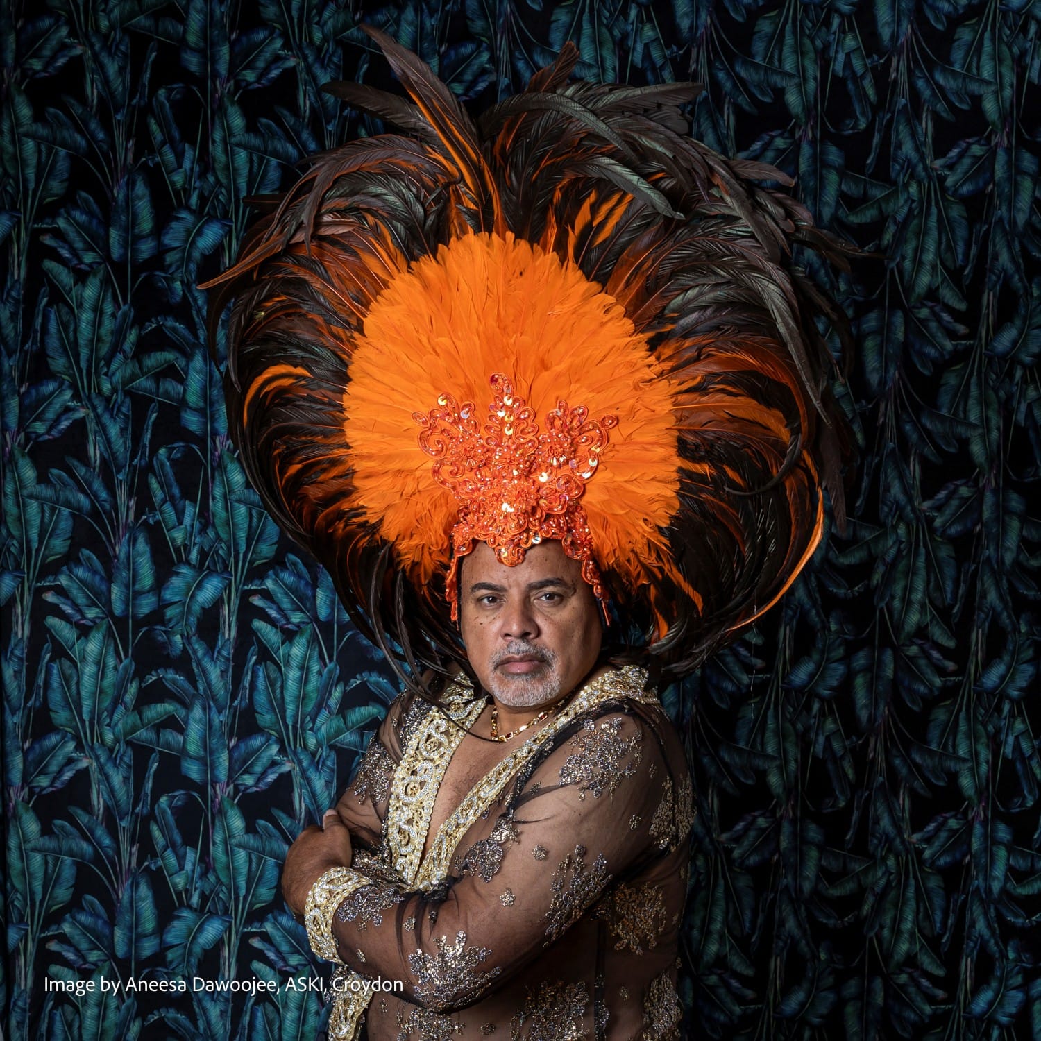 Joseph Jefferson wearing vast carnival feathered headdress and sheer sequinned jacket
