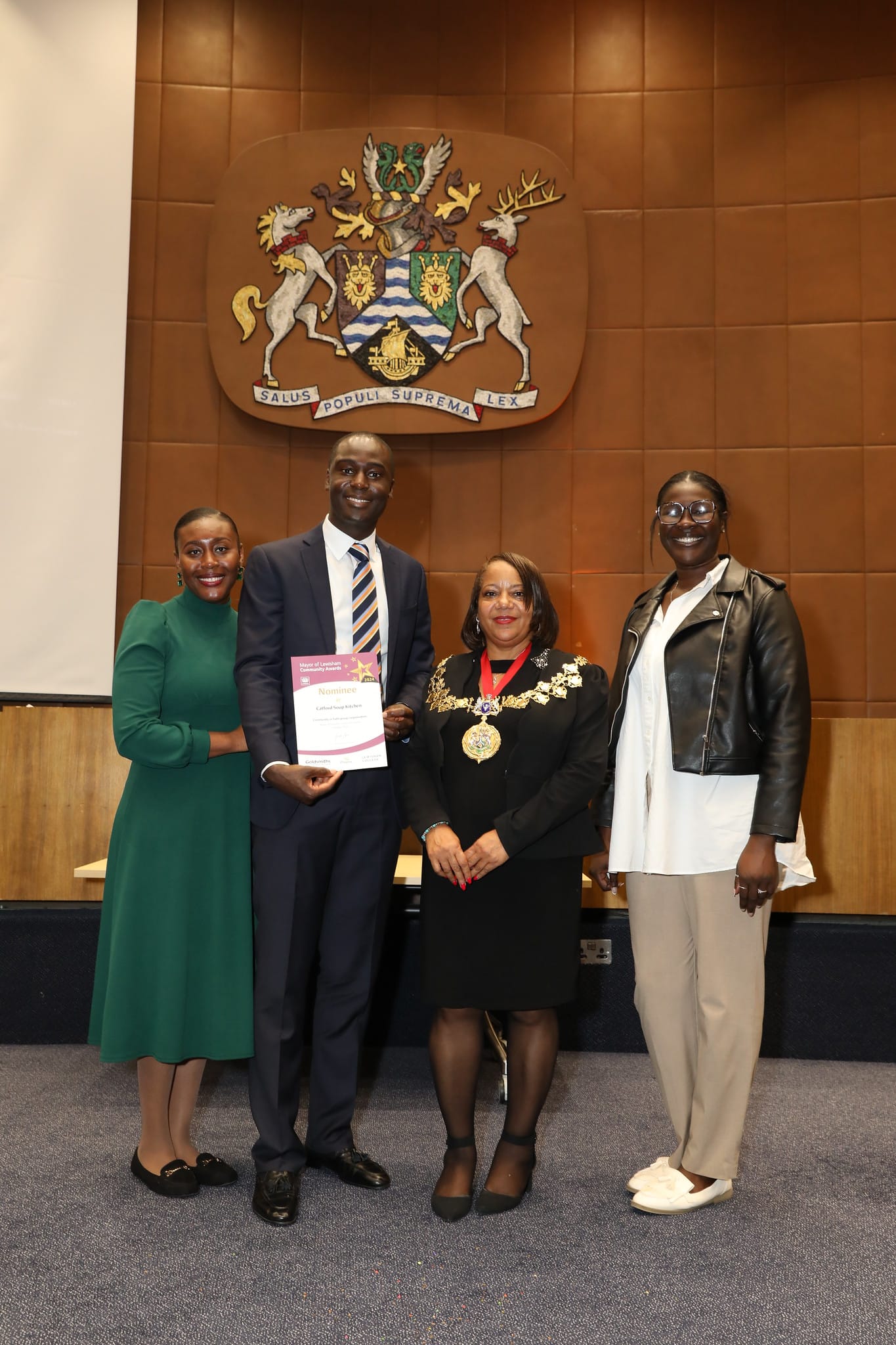 Photo 3 members of UCKG smiling, holding certificate at awards ceremony with mayor Brenda Dacres at centre