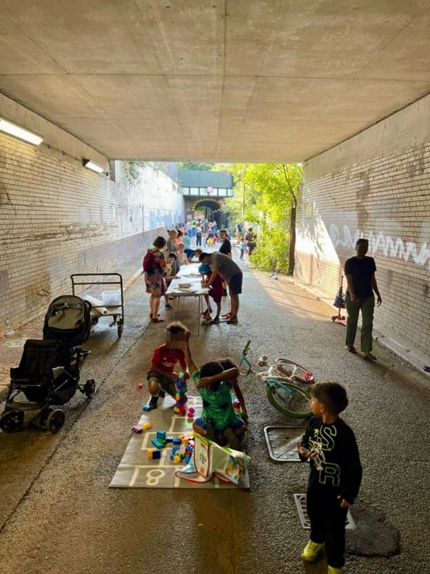 Play street day - tunnel closed to traffic, buggies parked, tressle tables and games on the floor, children and adults participating