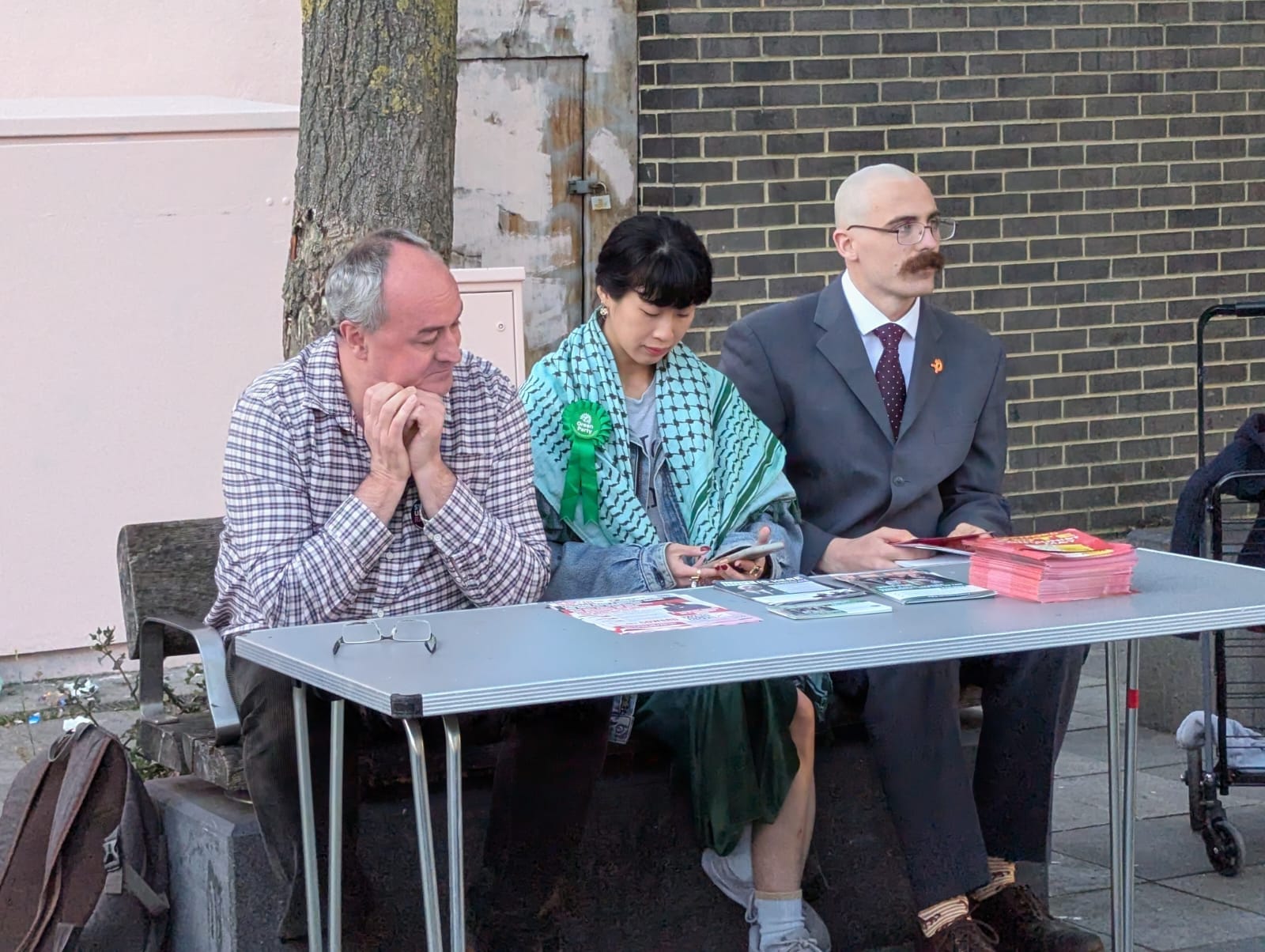 The three candidates sitting silently at a table, listening to a question.
