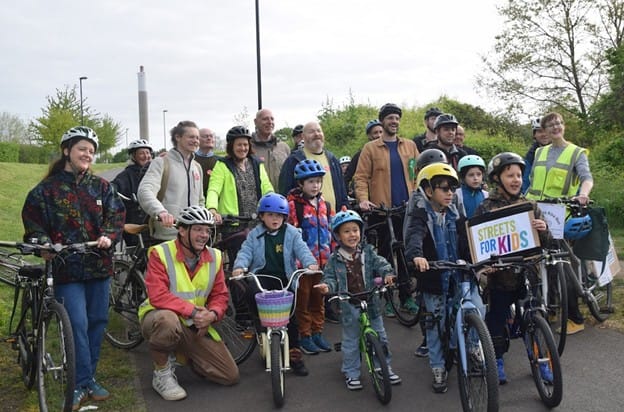 Group photo of children and adults before the bus departs. Kids holding signs "Streets for Kids".