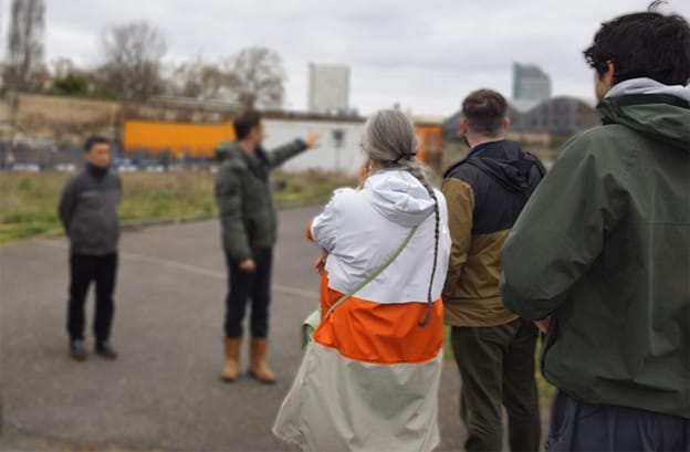 Residents and campaigners standing in coats listening to developer representatives at site visit 27 March. Rep is pointing out something on site.