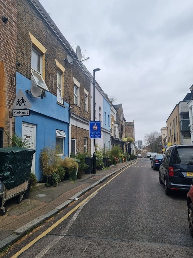 Tanners Hill - narrow road with planters on pavement, school sign and notice pointing to school street restrictions on turn off.