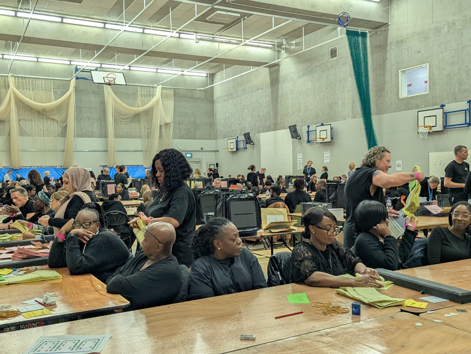 Staff sitting in school gym about to start counting ballots.