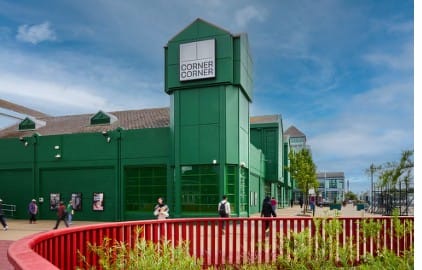 CGI of Corner, Corner -  bright green warehouse like building with tower. 
