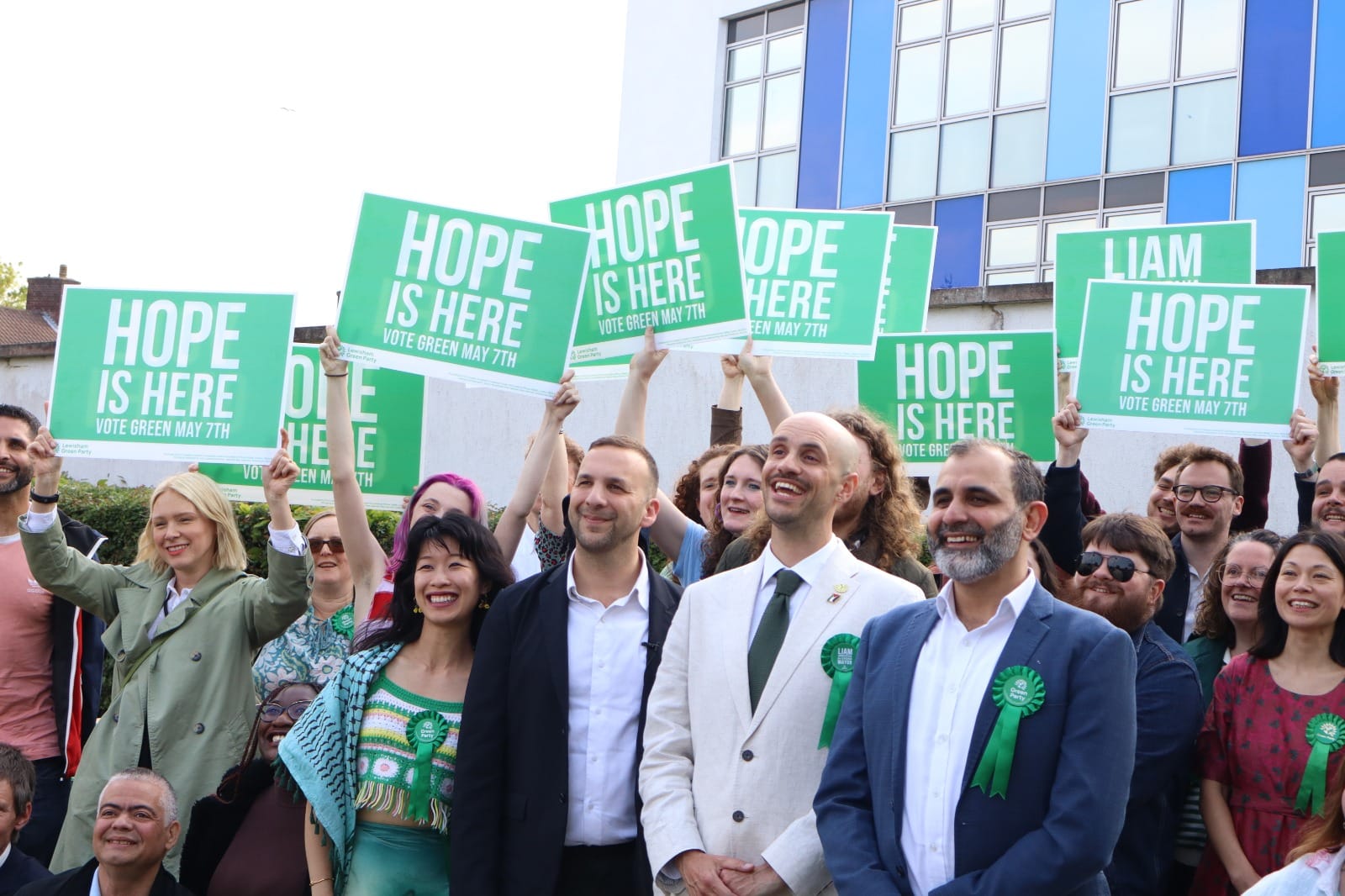 Zack Polanski, Liam Shrivastava and crowd of supporters holding signs "Hope is here".