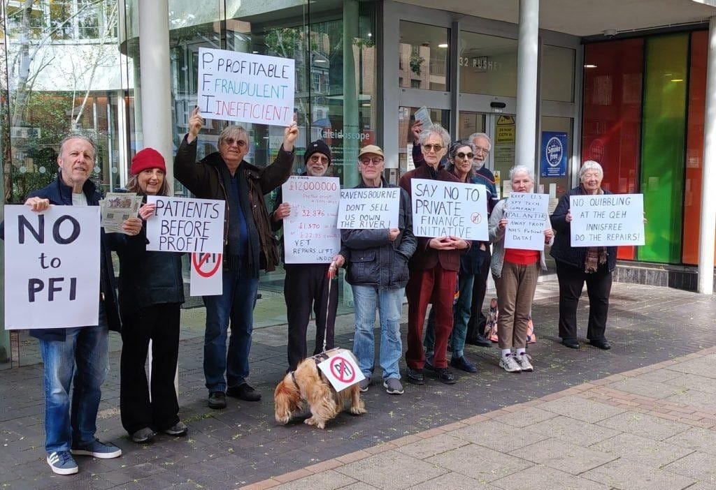 Campaigners from Reclaim the NHS and Unite the Community holding signs 'No to PFI' and 'Patients before Profit' at protest before board meeting.