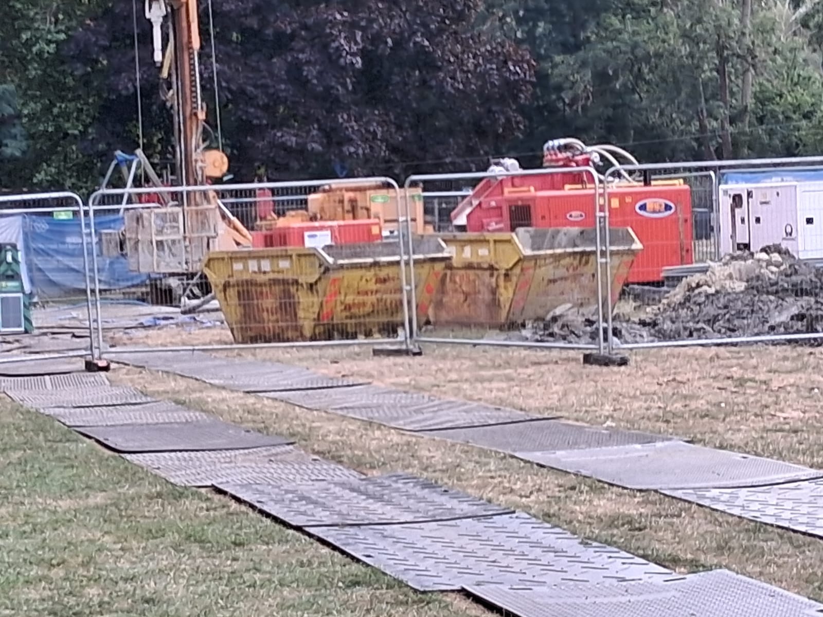 Tracking mats laid on dry grass between the two drilling rigs, and south drilling rig with skips.
