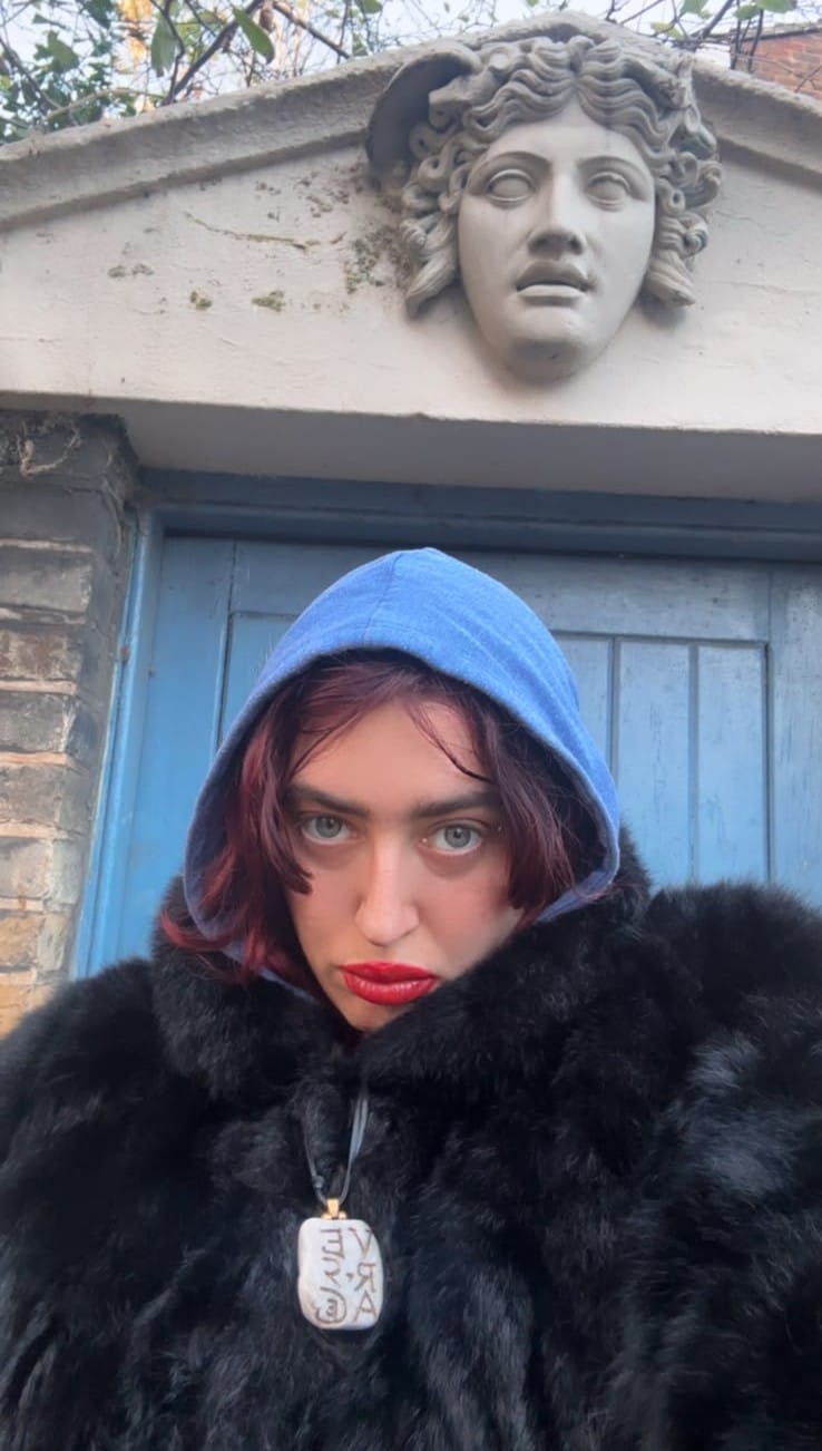 Selfie of Luna Carmoon, scowling in black fur and with hood up. 