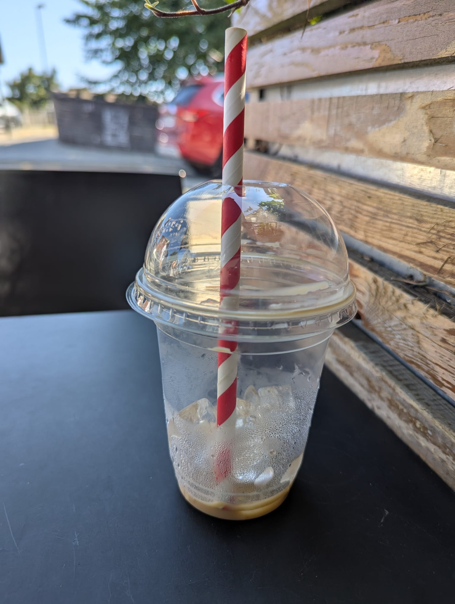Used iced coffee cup, clear plastic with ice at the bottom, straw through domed lid.