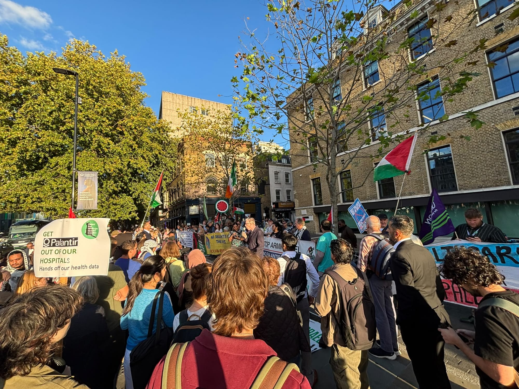 Huge rally outside London Hospital in evening sun, with Palestinian flags