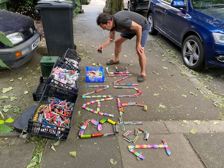 Paul de Zylva taking photo of vape litter on the pavement with vapes spelling out "Ban 1st June" 