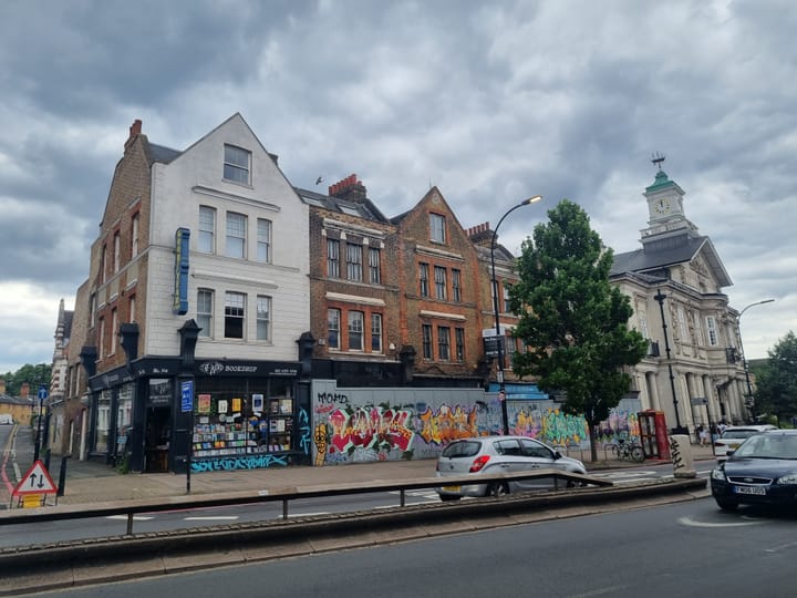 Parade of buildings which are up for sale - boarding with graffiti in front of vacant shops
