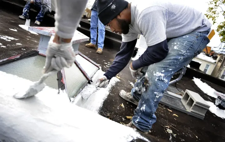 Workers painting a roof white