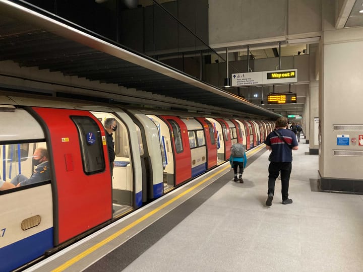 Tube train with doors open and passengers on platform. 