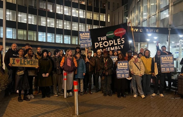 Protestors with banner "The People's Assembly" rally outside Lewisham Town Hall before the meeting.