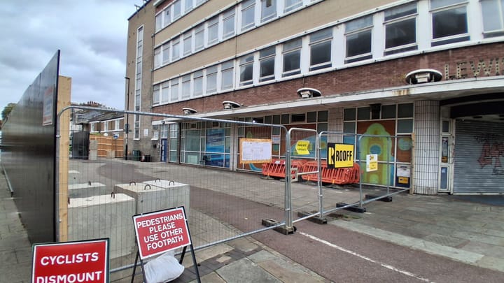 Fencing around the front of the library, with sign from construction company Rooff. 