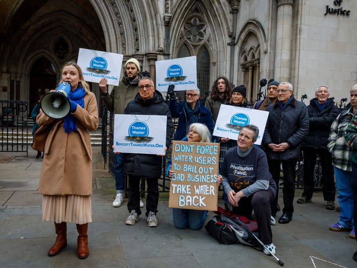 Protestors with signs showing Thames Water logo in pool of sewage and calls to "take water back". 