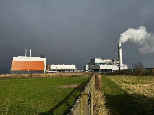Cory's 2 incinerators at Crossness against dark sky, heavy  smoke coming out of chimney at Riverside 1.
