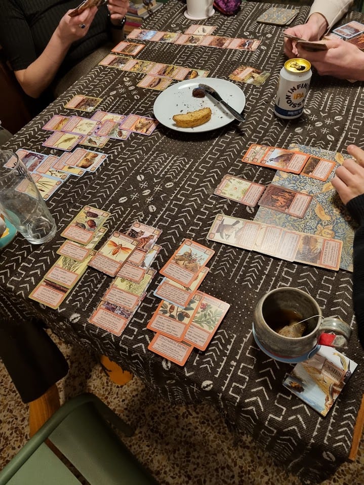Table laid out with board game Ecologies and hands of people playing. 