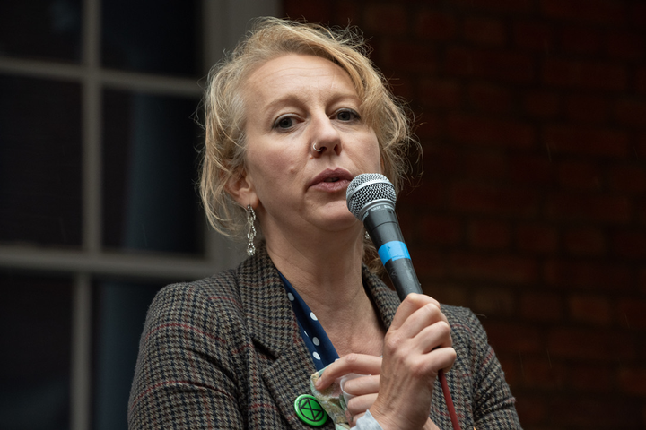 Gail Bradbrook in tweed jacket, XR badge and holding microphone. 