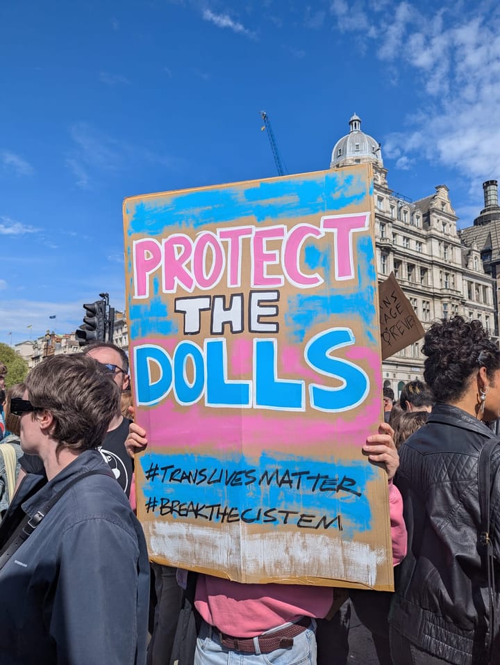 Protest in Trafalgar Square, placard stating Protect the Dolls, #TransLivesMatter  