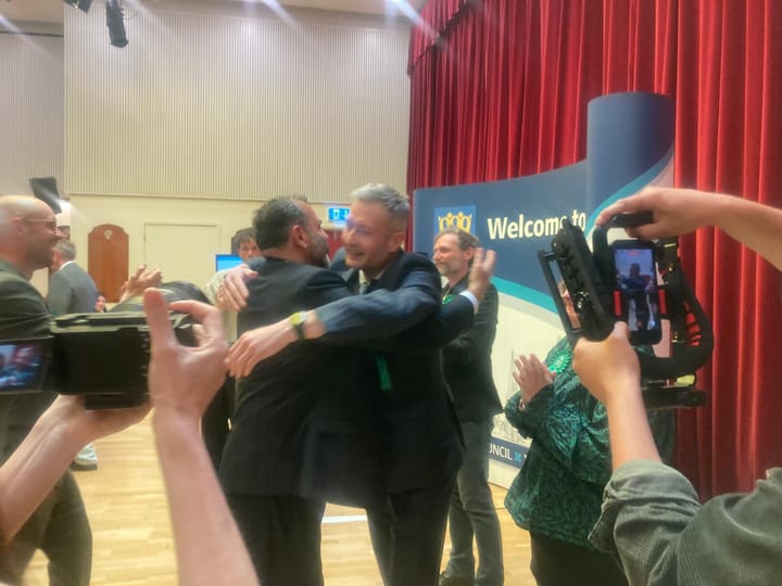 New councillor being hugged in congratulations from departing Green councillor Tauseef Anwar. 