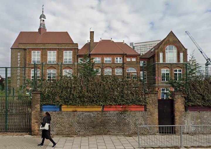 Large Victorian red brick primary school, cranes in background. 
