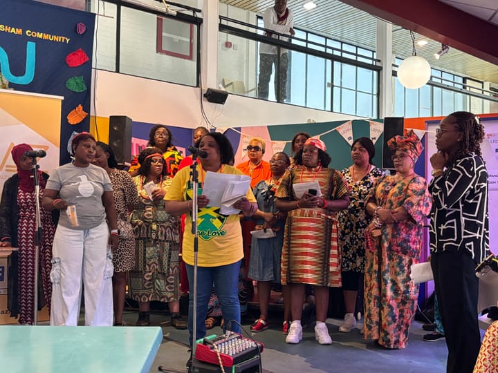Choir standing behind a woman at a microphone, waiting to sing. 