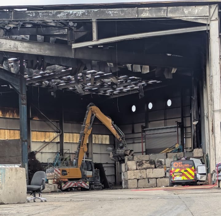 crane moving debris at the burnt out warehouse. 