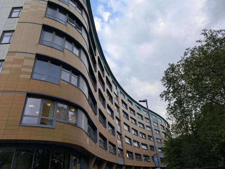 Riverside wing of Lewisham hospital - 6 storey curved building with brown facade.