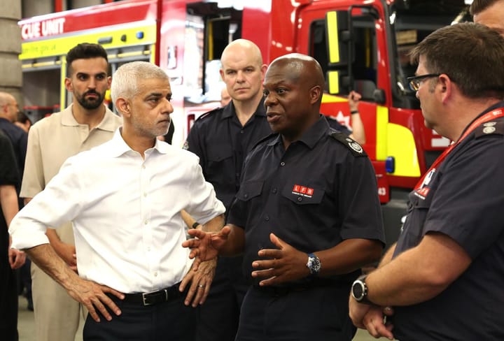 Sadiq Khan speaks with London Fire Brigade members at the Heat Ready London report launch. Fire engine visible in background.