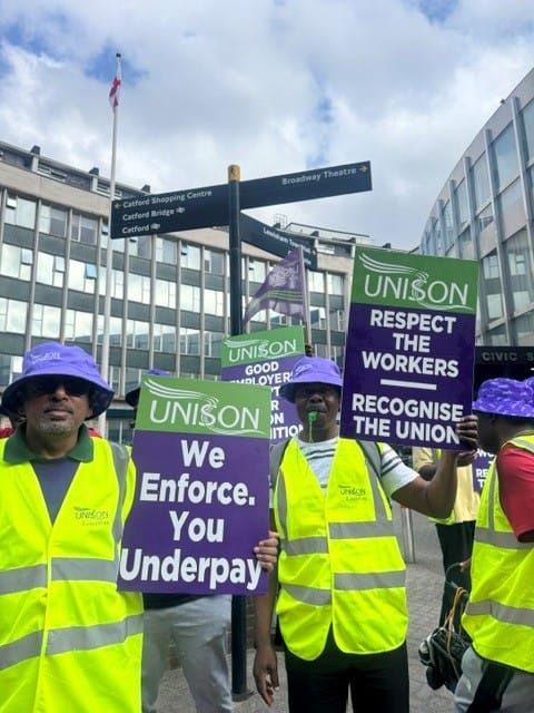 Officers in hi-vis jackets in picket line outside the town hall with placards: "Respect the Workers, Recognise the Union".