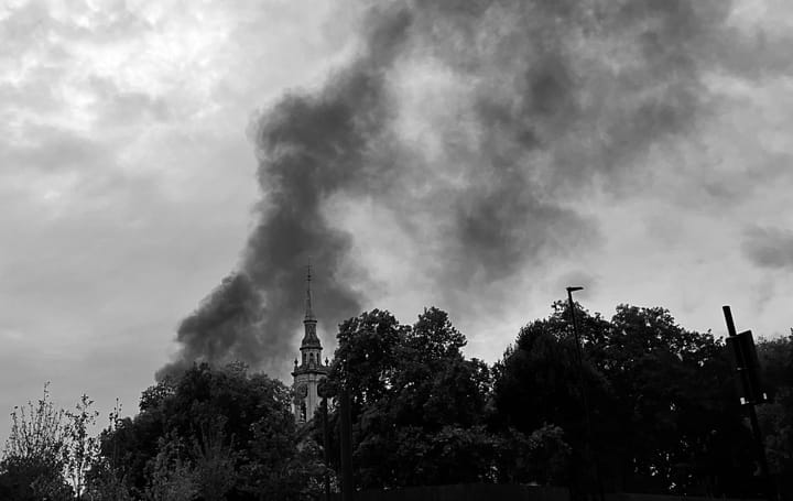 Smoke from the fire rising above tree tops and spire of St Paul's Church Deptford.
